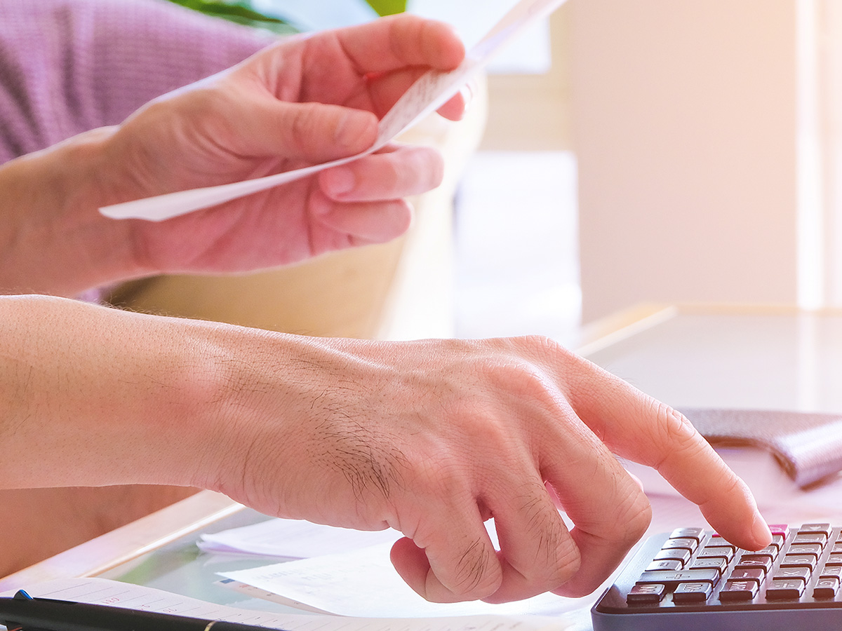 Man using calculator, holding invoice and check his salary for plan personal expense budget.