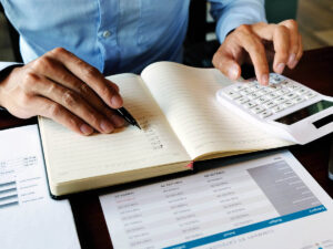 A worker with a calculator comparing numbers. 